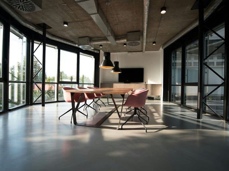 Loft studio with glazed walls, concrete ceiling and a long table