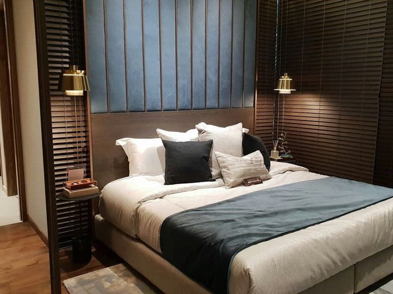 Hotel bedroom with a panelled headboard and warm wall lights