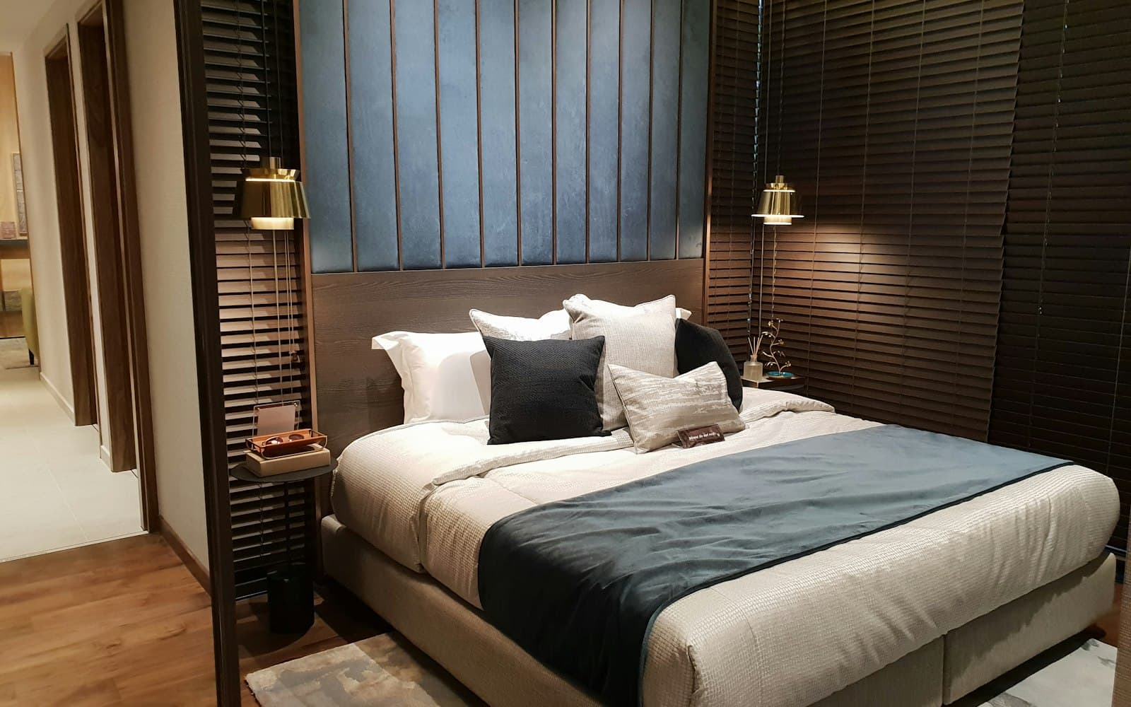 Hotel bedroom with a panelled headboard and warm wall lights