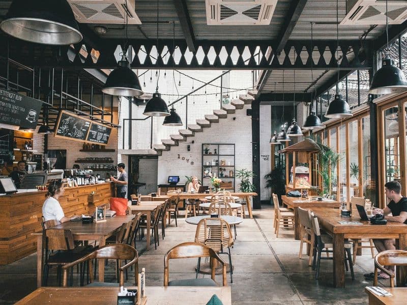 Double-height café with timber tables and industrial lighting
