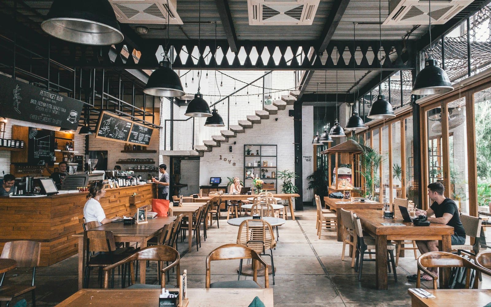 Double-height café with timber tables and industrial lighting