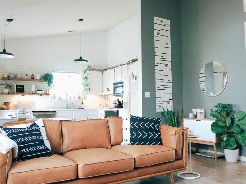 Tan leather sofa in a bright, plant-filled living room