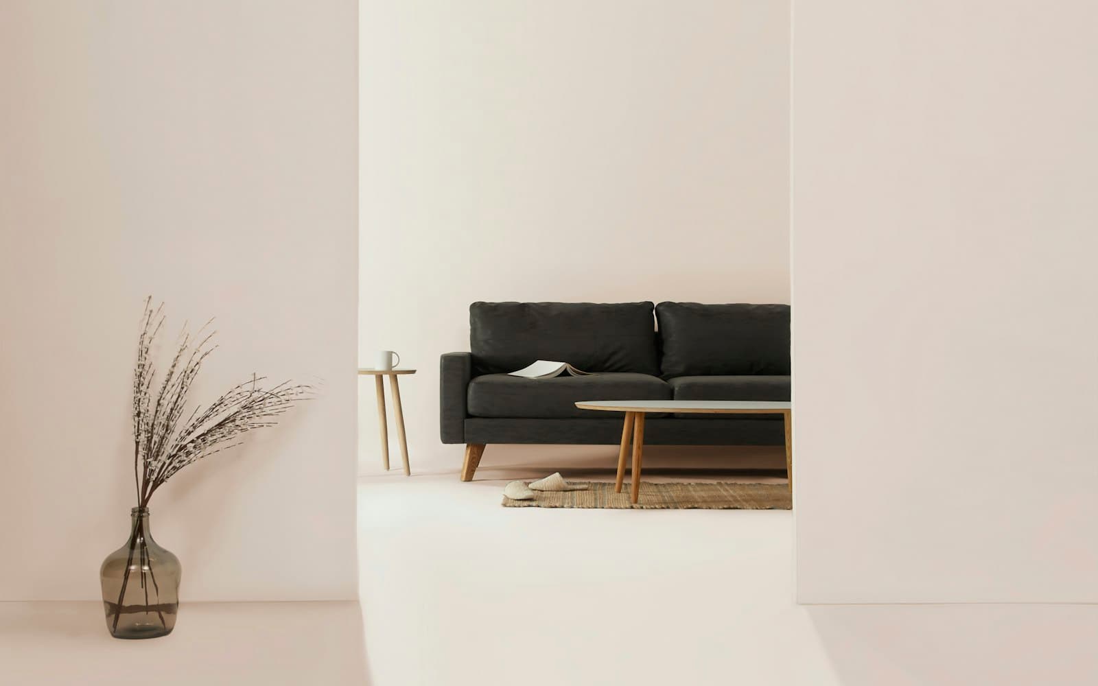 Minimal white living space with a low sofa and dried grasses