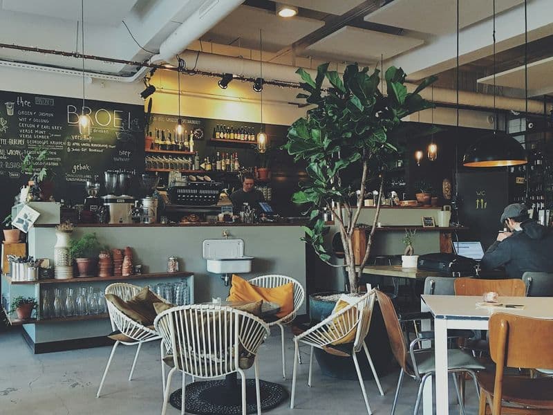 Café interior with a chalkboard menu, plants and woven chairs