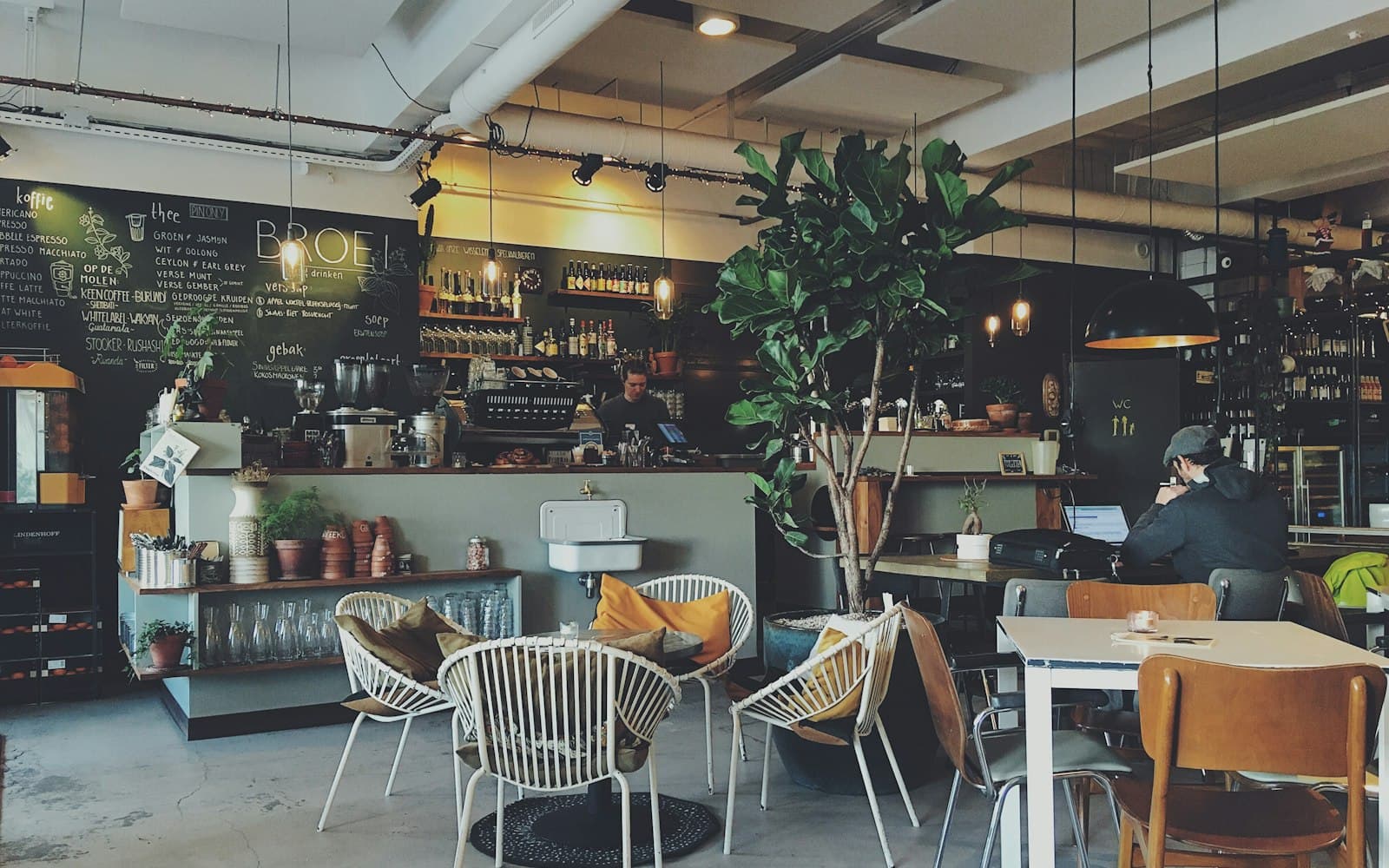 Café interior with a chalkboard menu, plants and woven chairs