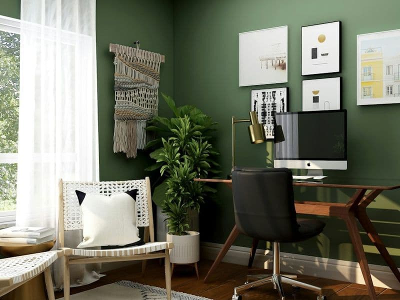 Green-walled home studio with a desk and framed prints