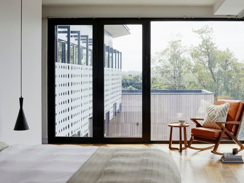 Bedroom with floor-to-ceiling glazing and a leather lounge chair