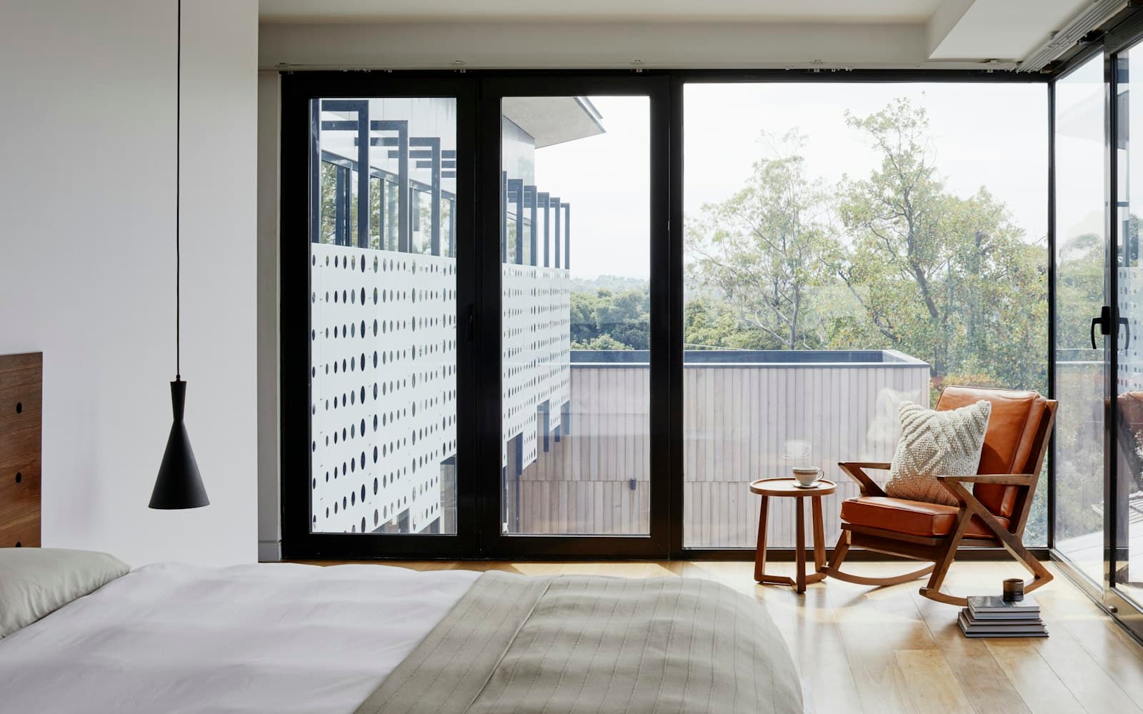 Bedroom with floor-to-ceiling glazing and a leather lounge chair