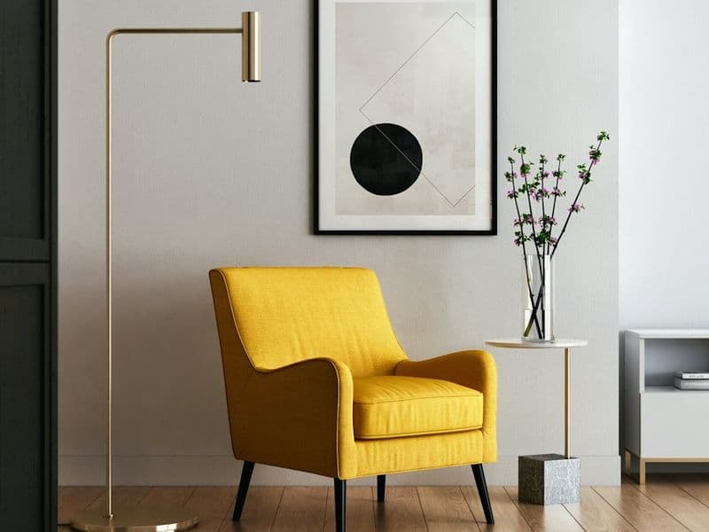 Yellow armchair and floor lamp against a white wall